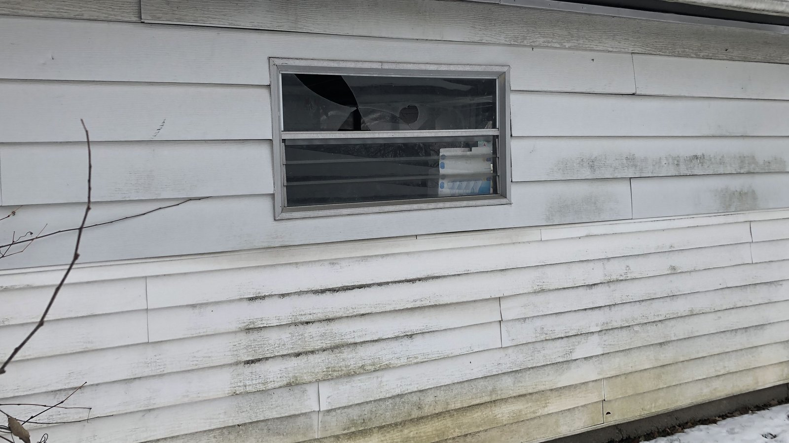 Dark water staining running down siding below a gutter